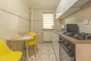 a kitchen with a stove and a table and yellow chairs at Luxury 2 bedroom holiday apartment in Piteşti