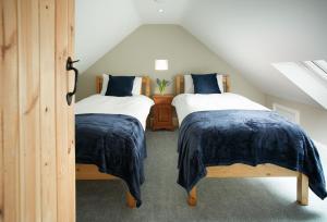 a attic bedroom with two beds with blue sheets at Kirby Cottage in Harome