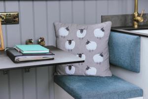 a pillow with a flock of sheep on it on a shelf at Spinney View Huts 