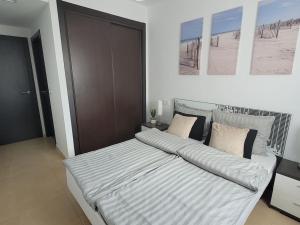 a bedroom with a large bed with striped sheets at La Mata Azul Beach 2 in Torrevieja +20 photos