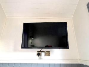 telewizor z płaskim ekranem wiszący na ścianie w obiekcie Spinney View Huts 