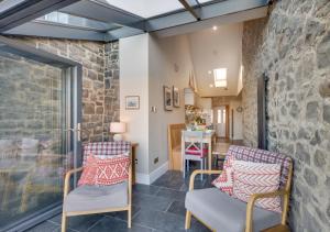 a living room with two chairs and a stone wall at Harbour Masters House in Craster