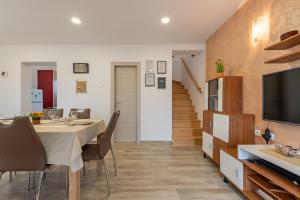 a dining room with a table and chairs and a television at R&B Family Apartments in Sveti Filip i Jakov