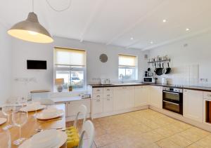 a kitchen with white cabinets and a table with chairs at Seasalt in Swinhoe