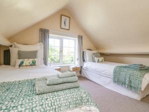 Un dormitorio abuhardillado con dos camas y una ventana. en Charlesworth, en Ashford