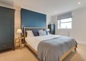 a bedroom with a large bed with a blue wall at Coastguard Cottage in Craster