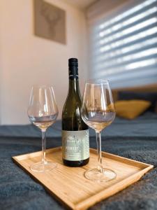 a bottle of wine and two wine glasses on a cutting board at Nordin Apartman in Hódmezővásárhely