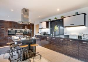 a kitchen with wooden cabinets and bar stools at Beadnell Beach House in Beadnell
