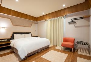 1 dormitorio con 1 cama y 1 silla roja en The Cloud Hotel en Zhubei