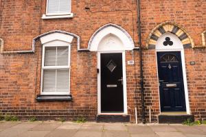 two black doors on a brick building with windows at Rose Cottage in Shrewsbury