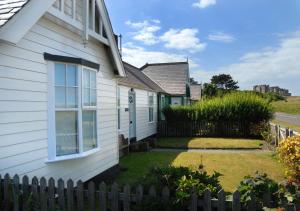 uma casa branca com uma cerca ao lado de um quintal em Bamburgh Beach House em Bamburgh