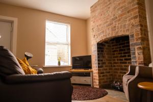 a living room with a brick fireplace and a couch at Rose Cottage in Shrewsbury