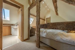a bedroom with a wooden bed and a bathroom at The Garden Barn in Peterchurch