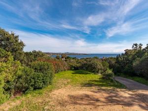 a dirt road with trees and the ocean in the background at Holiday Home Villa Bruzzi by Interhome in Pianottoli-Caldarello