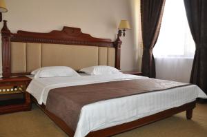 a bedroom with a large bed with a wooden headboard at Firuz Hotel in Khujand