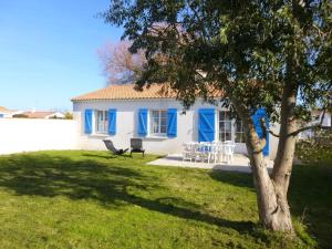 una casa con porte blu e un cortile con un albero di Maison lumineuse avec jardin clos, à 400m de la plage, pour 8 personnes, secteur calme - FR-1-224B-22 a LʼÉpine