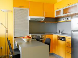 eine Küche mit orangefarbenen Schränken und einer Schale Obst auf dem Tisch in der Unterkunft Apartment Olivia by Interhome in Balatonőszöd