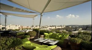 Un patio con una mesa y sillas y una sombrilla. en Spa on the walls - Mamilla View - Jerusalem ספא על החומות ירושלים, en Jerusalén