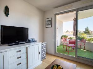 - un salon avec une télévision et une table avec des chaises dans l'établissement Apartment Le Lagon Bleu by Interhome, à Cagnes-sur-Mer