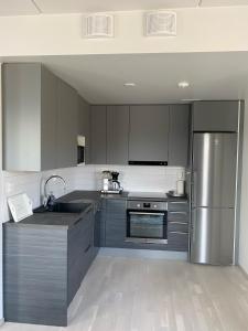 a kitchen with gray cabinets and a stainless steel refrigerator at BOSSHOMES Apartments Espoo - Close to Helsinki and access to Airport in Espoo