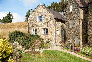 an old stone house with a garden in front of it at Unconformity Barn in Hope Bowdler