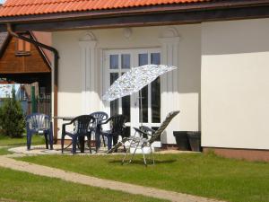 a group of chairs and an umbrella in front of a house at Holiday Home Domek Joanna-5 by Interhome in Łeba