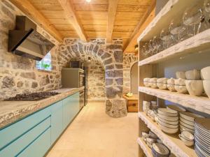 a kitchen with blue cabinets and a stone wall at Holiday Home Jerini Main House by Interhome in Vrh +28 photos