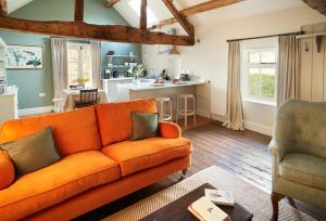 a living room with an orange couch and a kitchen at The Groom's Flat in Leominster