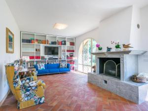 a living room with a fireplace and a blue couch at Villa Loris-2 by Interhome in Riparbella