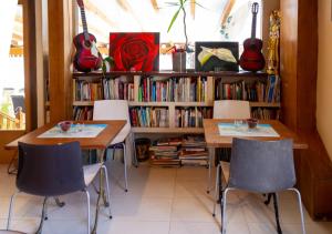 dos mesas y sillas frente a un estante de libros con guitarras en Agua Viva Eco H Wellness Castro Urdiales, en Castro Urdiales