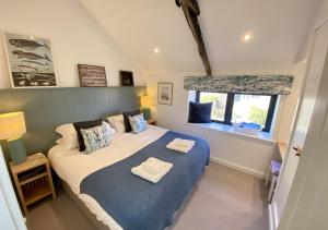 a bedroom with a bed with blue sheets and a window at Red Herring in Craster
