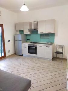 een keuken met witte kasten en een fornuis met oven bij Mini appartamento in campagna in Castagneto Carducci