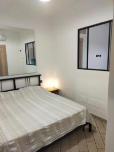 een witte slaapkamer met een bed en een spiegel bij Mini appartamento in campagna in Castagneto Carducci