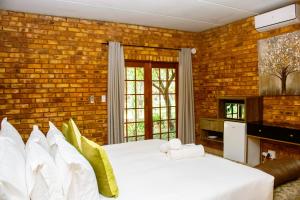 1 dormitorio con 2 camas y pared de ladrillo en Mela Luxury Game Lodge, en Pretoria