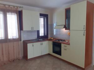 uma cozinha com armários brancos e um forno com placa de fogão em Relax Apartment in San Vito em San Vito lo Capo