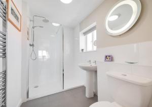 a white bathroom with a shower and a sink at Seafarers in Seahouses