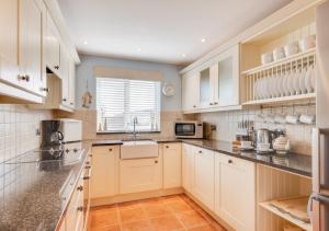 a kitchen with white cabinets and a sink at Seafarers in Seahouses