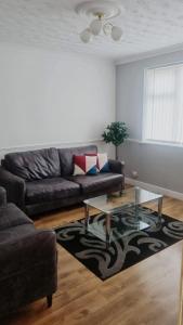 a living room with a leather couch and a glass table at Spacious Luxurious Serviced Accomodation in Doncaster