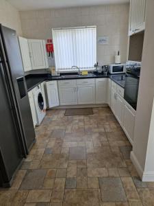 uma cozinha com armários brancos e piso em azulejo em Spacious Luxurious Serviced Accomodation em Doncaster