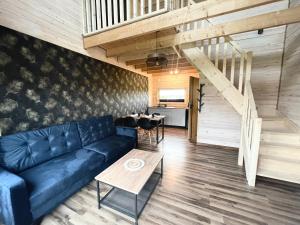a living room with a blue couch and a staircase at BALTICO Domki Letniskowe in Sarbinowo
