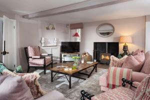 a living room with couches and a table and a fireplace at The Gables in Cow Honeybourne