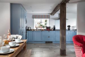 a kitchen with blue cabinets and a wooden table at The Gables in Cow Honeybourne