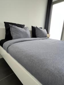 a large bed with gray sheets and pillows at FDS Cosy Apartment in Ghent