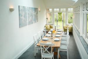 a dining room with a long table and white chairs at Dolbelidr in St Asaph