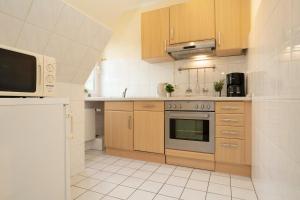 a kitchen with wooden cabinets and a microwave at Haus Seepferdchen am Meer Appartement 7 in Timmendorfer Strand
