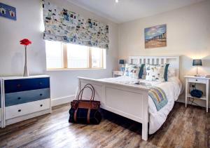 a white bedroom with a white bed and a window at Quayside in Amble
