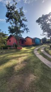 un groupe de maisons dans un champ avec un arbre dans l'établissement Pousada Sítio Val Paraíso, à Sana