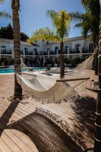 a hammock in a resort with palm trees and a pool at Paloma Blanca Boutique Hotel- Adults Recommended in Marbella