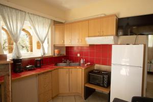 a kitchen with wooden cabinets and a white refrigerator at Yukas Home Xylokastro for 3 persons by MPS num 1 in Xylokastron