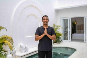 un hombre está parado frente a una casa con meditación en Aesthetic Villa 1bed with private rooftop and pool, Casa Alba, Canggu Pererenan, en Canggu